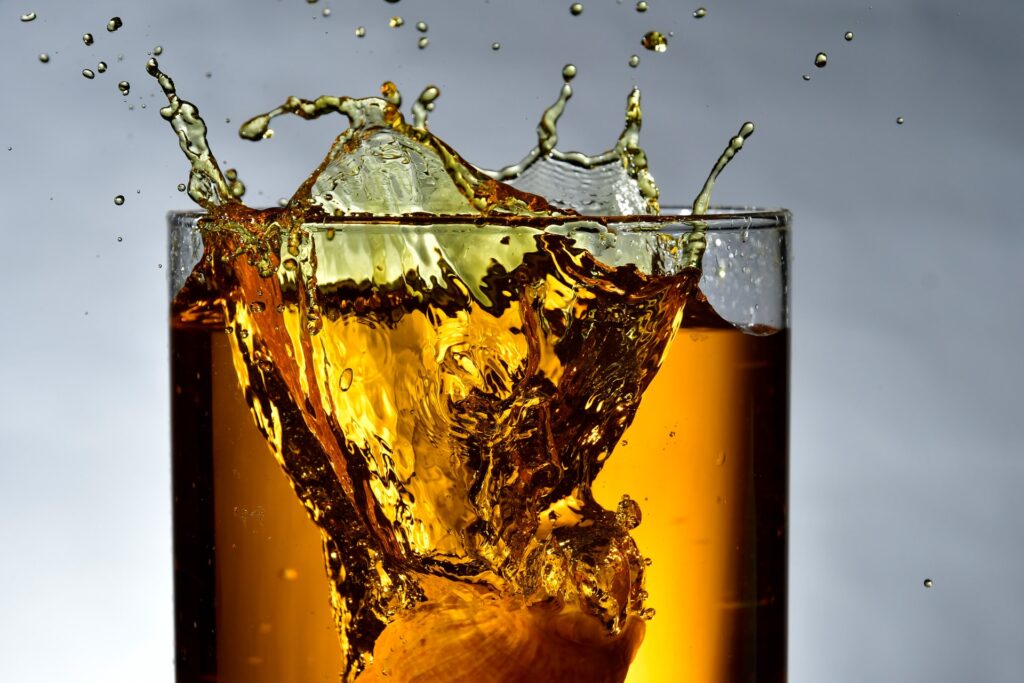 glass of whiskey with an ice cube in